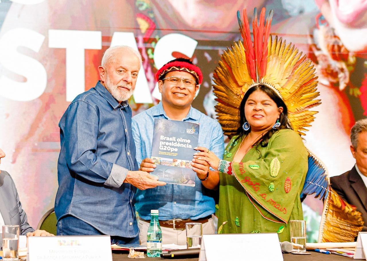 El Presidente Luís Inácio Lula da Silva recibe el e-book del G20 Brasil en guaraní junto a Sonia Guajajara, Ministra de Pueblos Indígenas de Brasil, y Eliel Benites, que tradujo el boletín | Foto: Audiovisual G20 Brasil